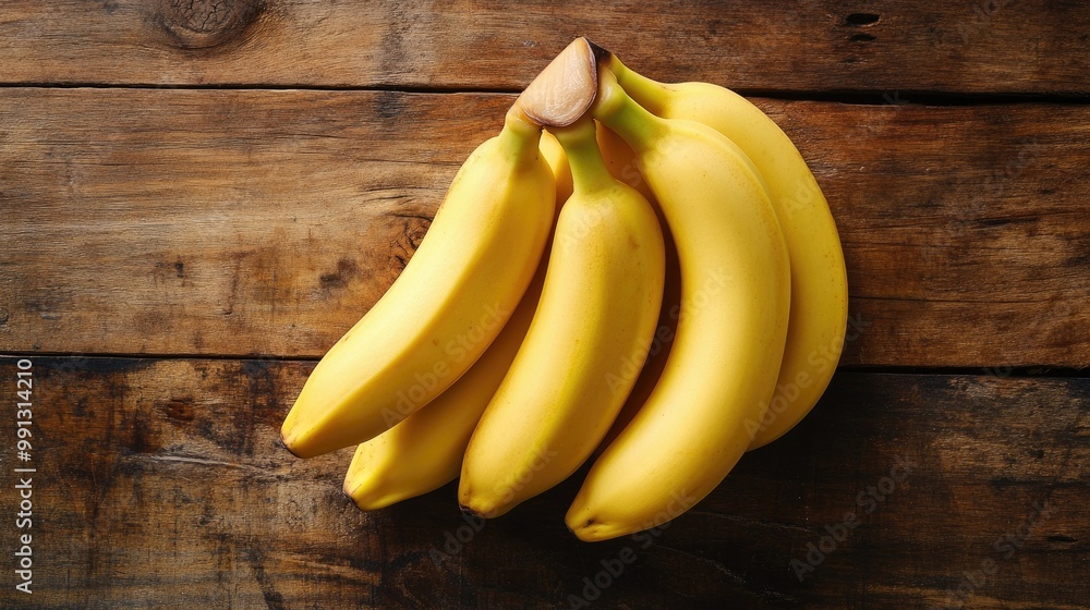 A bunch of organic yellow bananas arranged neatly on a rustic wooden table, with soft natural light highlighting their smooth, vibrant skin. A bunch of organic yellow bananas arranged neatly on a rustic wooden table, with soft natural light highlighting their smooth, vibrant skin.
