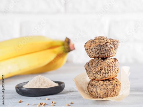 Healthy gluten-free homemmade banana muffins with buckwheat flour. Stack of three vegan muffins with poppy seeds on gray wooden table. Copy space photo