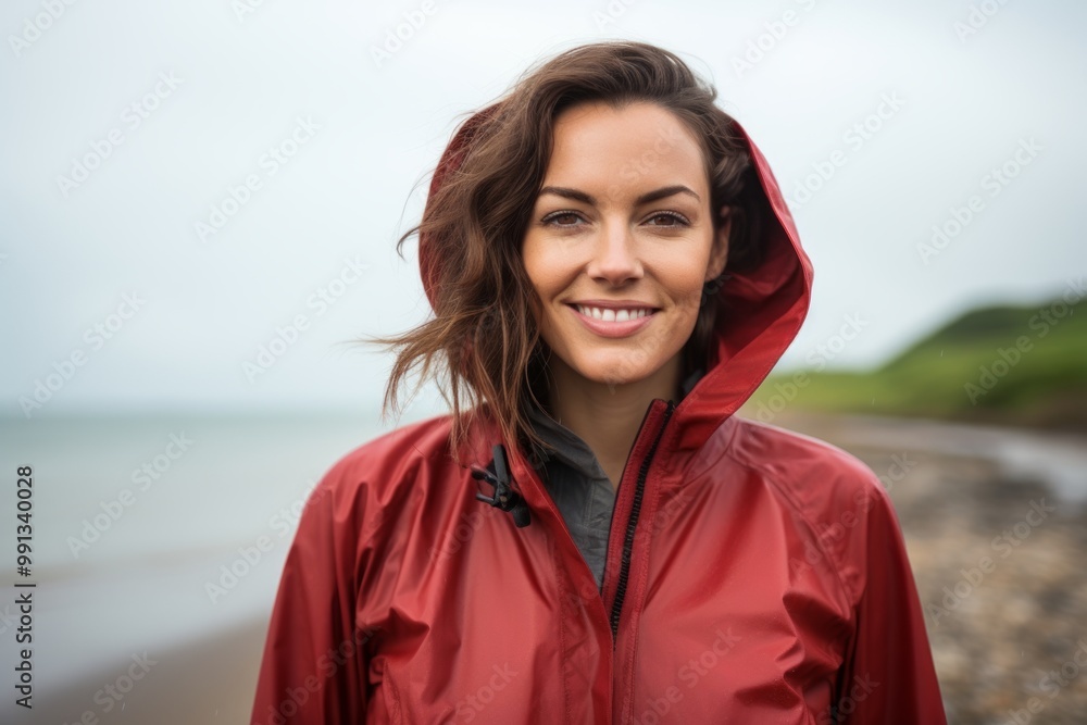 Portrait of a merry woman in her 30s sporting a waterproof rain jacket on calm bay background Portrait of a merry woman in her 30s sporting a waterproof rain jacket on calm bay background