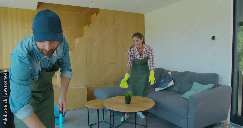Professional cleaners in uniform washing floor and wiping dust from the furniture in the living room of the apartment. Cleaning service concept. Professional cleaners in uniform washing floor and wiping dust from the furniture in the living room of the apartment. Cleaning service concept.
