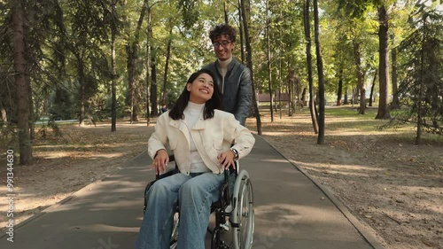 Boyfriend pushing girlfriend in wheelchair smiling and raising arms