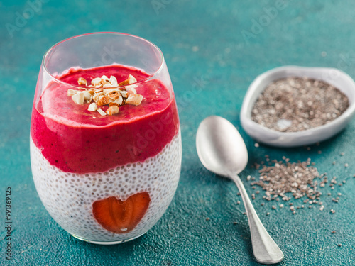 Idea for healthy breakfast on Valentine's Day: Chia pudding with red berry puree, chopped almonds on top and strawberry in the shape of heart. Copy space for text