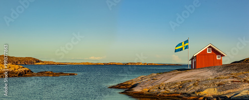 Rotes Schwedenhaus mit Schwedischer Falgge an der Küste am Meer