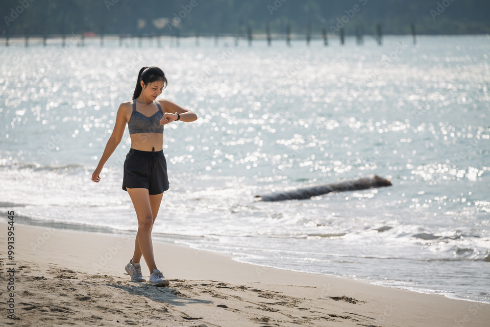 Asian runner healthy woman using smart watch and run on the beach Thailand Asian runner healthy woman using smart watch and run on the beach Thailand