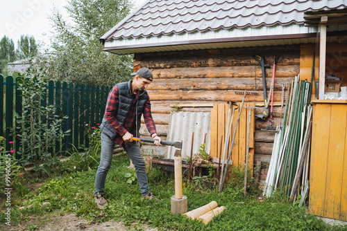 A man is chopping wood in his backyard, embracing a rustic outdoor lifestyle that embodies the essence of labor and craftsmanship