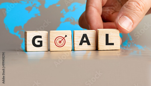 Goal Achievement Concept with Wooden Cubes and Target Symbol, Business Strategy and Success Visualization, Hand Setting Goal Block with World Map in Background.