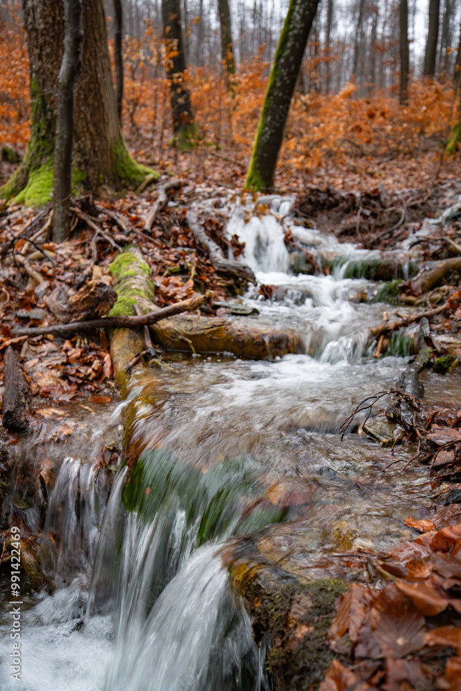 A small mountain stream is coming down a hill in the autumn forest A small mountain stream is coming down a hill in the autumn forest