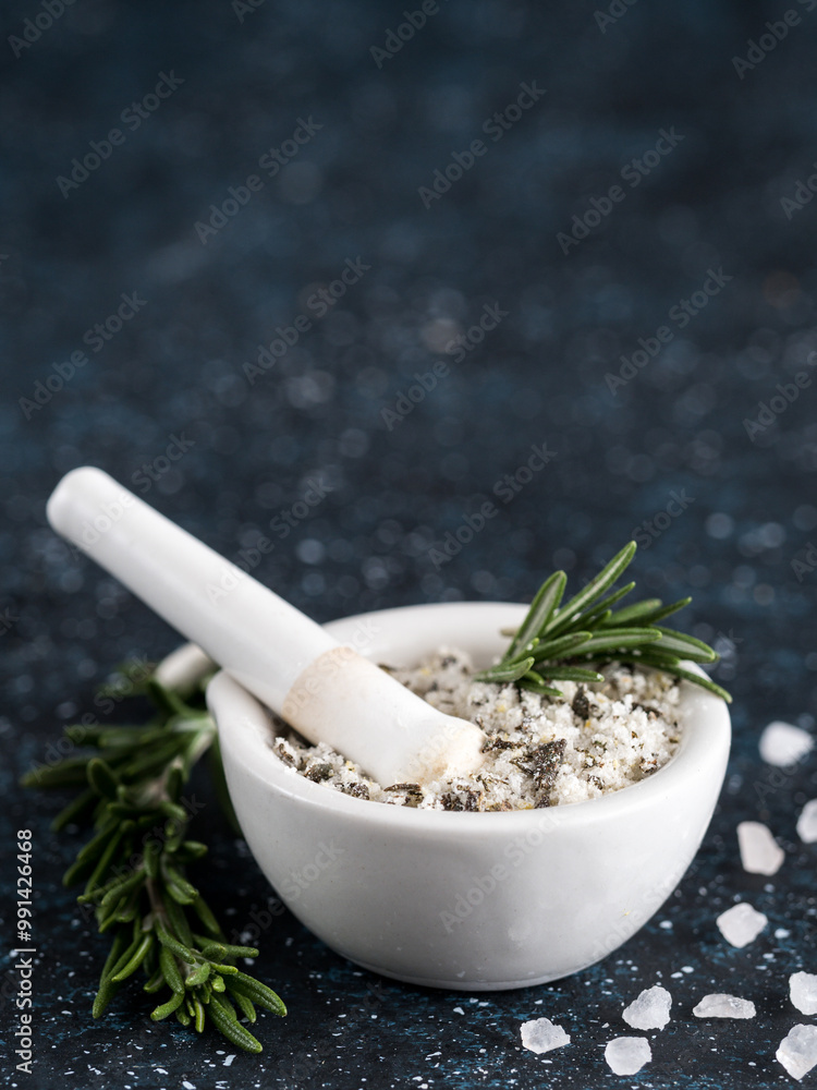 Close up view of mortar and pestle with sea salt scented rosemary and lemon zest. Sea salt scented herb rosemary on dark blue background. Scented salt and ingerdients. Copy space Close up view of mortar and pestle with sea salt scented rosemary and lemon zest. Sea salt scented herb rosemary on dark blue background. Scented salt and ingerdients. Copy space
