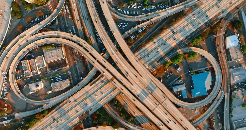 Transport moving by the highways, loops and freeways of a complicated road system. Top view on the famous interchange of Los Angeles, California, USA at sunset. Transport moving by the highways, loops and freeways of a complicated road system. Top view on the famous interchange of Los Angeles, California, USA at sunset.