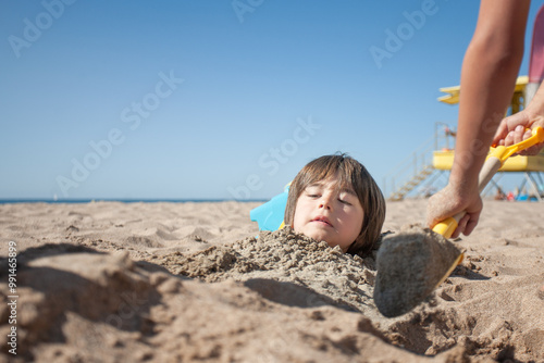 Boy with a worried face when he sees himself buried under the sand on the beach. photo