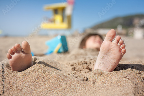 Obraz na plátně Close-up of the feet of a child who has been buried in the sandy beach
