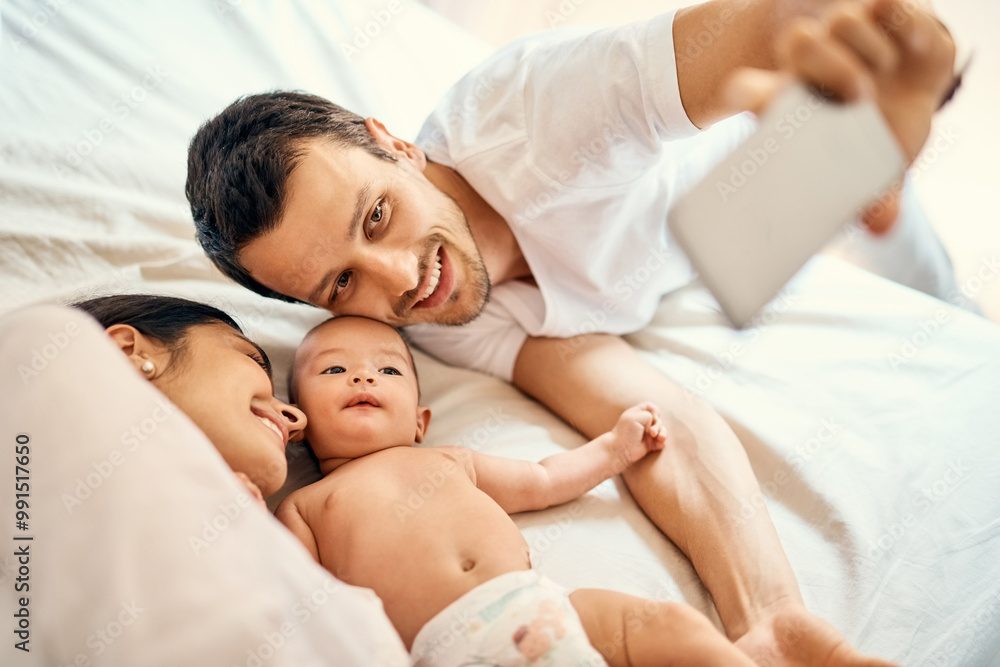 Mom, dad and baby on bed for selfie with smile, love and family in home for happy memory. Photography, parents and newborn infant in bedroom with support for growth, development or bonding in morning Mom, dad and baby on bed for selfie with smile, love and family in home for happy memory. Photography, parents and newborn infant in bedroom with support for growth, development or bonding in morning