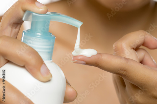 Tableau sur toile Close up woman hand pressing body lotion moisturizer cream from bottle pump