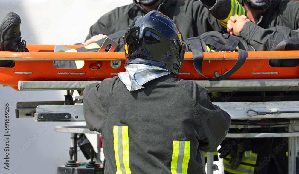 firefighter wearing a uniform and helmet carries a injured person on a stretcher firefighter wearing a uniform and helmet carries a injured person on a stretcher