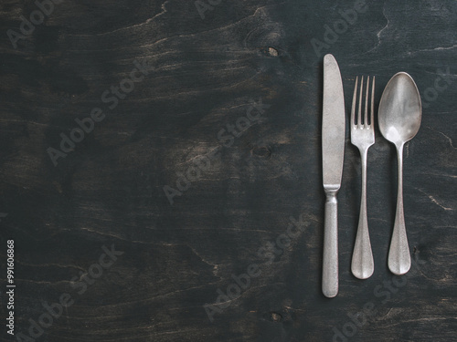 Vintage cutlery over dark background. Old tablespoon, fork and knife on black table. Top view or flat-lay. Copy space for text. photo