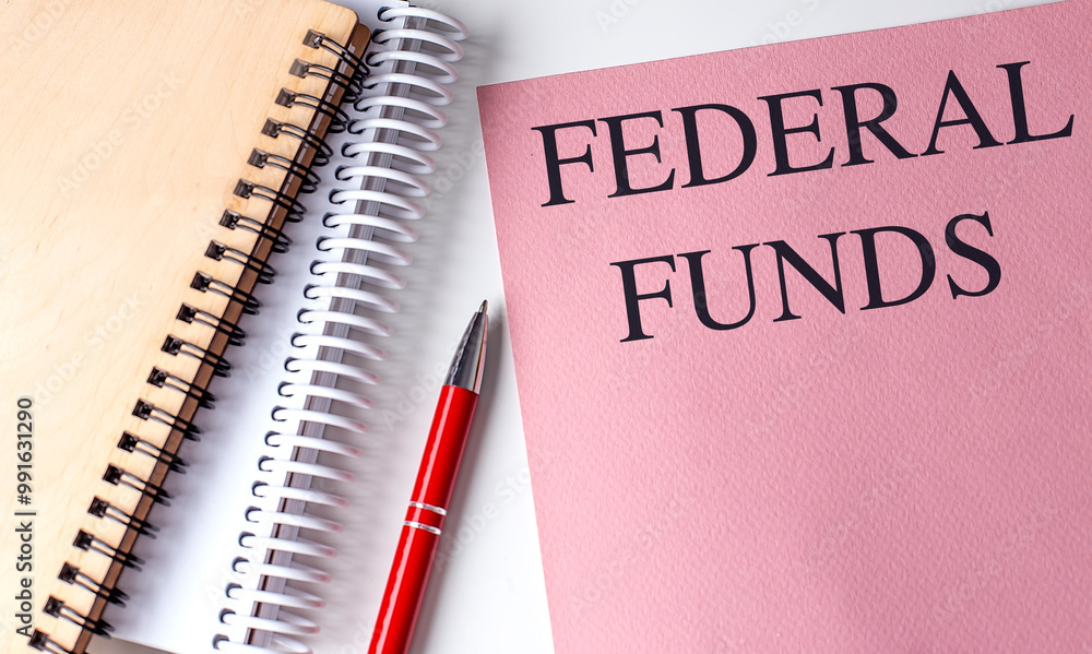 Federal funds text on pink notebook with two spiral notebooks and red pen on white background Federal funds text on pink notebook with two spiral notebooks and red pen on white background
