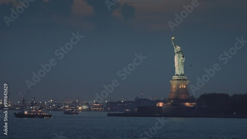 Waterfront view of the Statue of Liberty and New York harbor at night. The view of the statue from the boat. Visiting NYC.