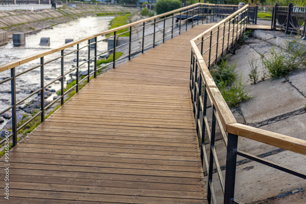 Wooden pathway along the riverside. River hiking trail in the city Wooden pathway along the riverside. River hiking trail in the city
