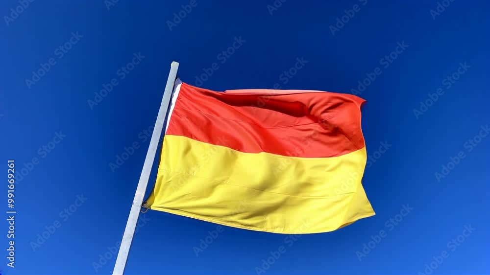 Red and Yellow Flag Waving Against a Clear Blue Sky Red and Yellow Flag Waving Against a Clear Blue Sky