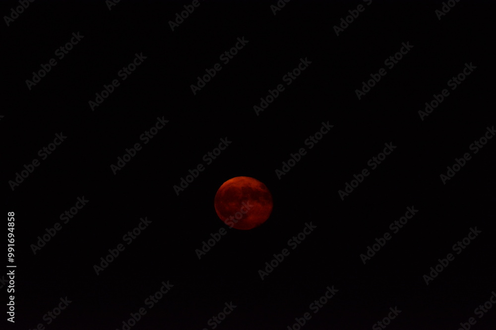 glowing red moon shining against a dark night sky glowing red moon shining against a dark night sky
