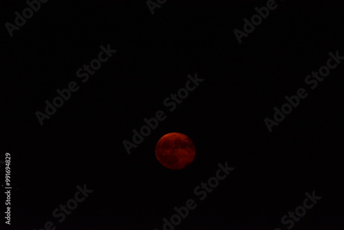 glowing red moon shining against a dark night sky photo