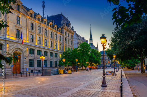 Fototapeta Naklejka Na Ścianę i Meble -  Paris street with lamp lights on sunset twilight in historic city center, Paris cityscape evening view, Place Louis-Lepine square with prefecture of police building on île de la Cite island, France