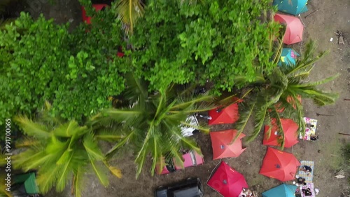 Madasari, Januari 13 2024 A dynamic aerial video showcasing campers enjoying their holiday near a beach. The scene features a variety of colorful tents set up on a campsite, with cars parked nearby photo