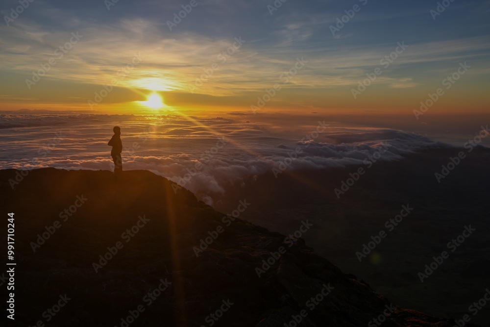 Obraz premium Une personne observe un coucher de soleil au sommet du Mont Pico