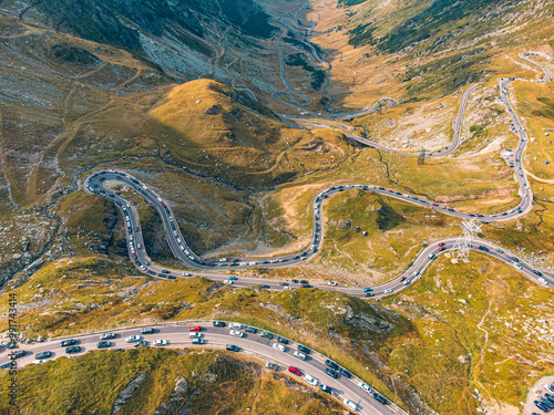 Aerial view of the Transfagarasan highway, highlighting the contrast of cars against the vibrant autumn trees.