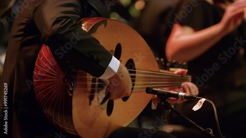 Steady shot of a male musician playing Oud instrument in an orchestra concert.