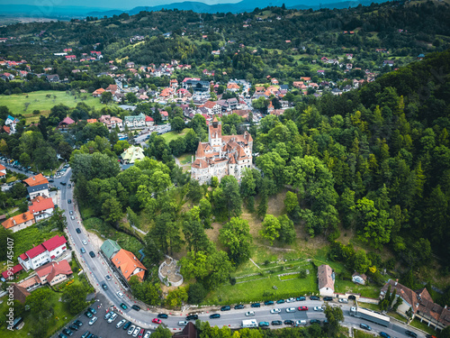  Aerial shot of Bran Castle with the majestic mountains in the background, illustrating its historical significance and scenic beauty.