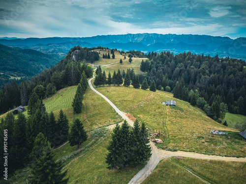  Aerial view of a panoramic landscape with green meadows and mountains on the horizon, showcasing nature's beauty.