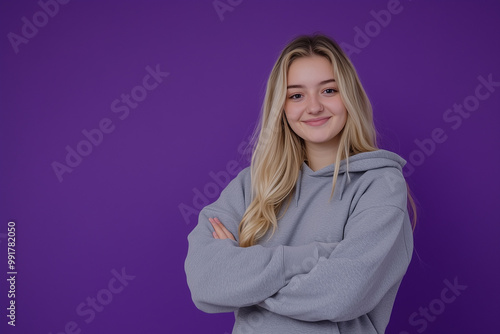 Student in hoodie and sweatpants against purple background with confident smile