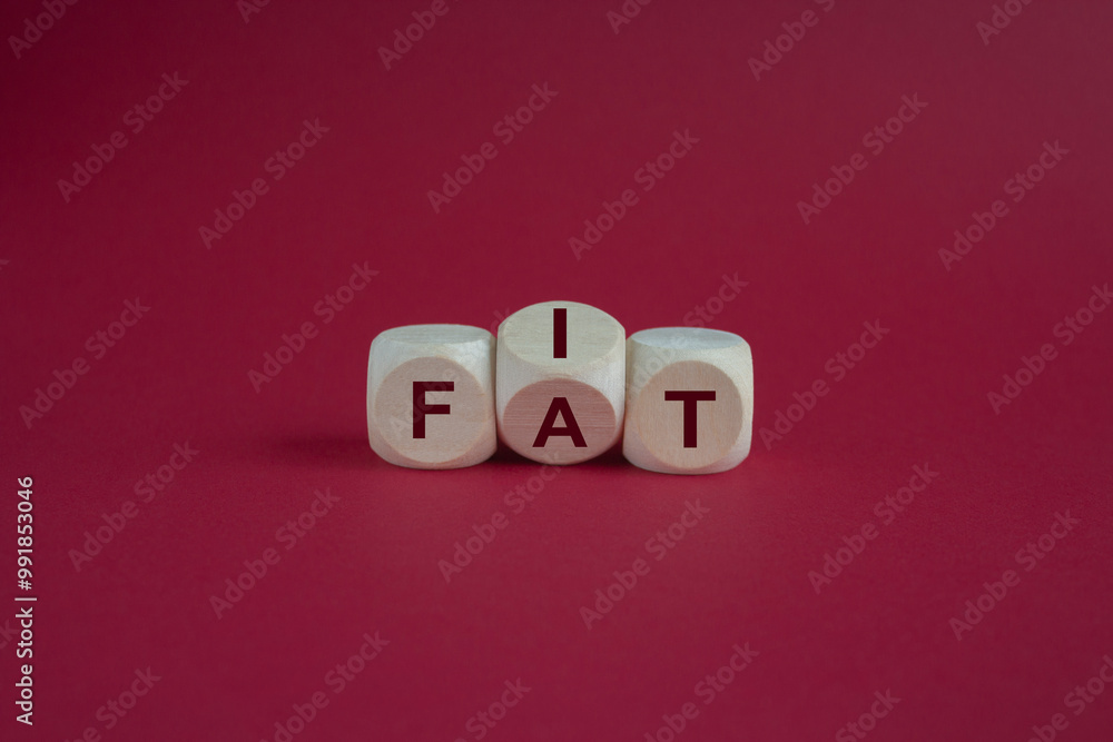 Turned a cube and changes the word fat to fit. Beautiful red background. Lifestyle and healthy concept.
