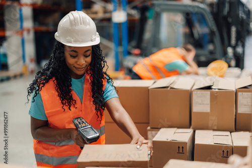 African american female warehouse worker scanning boxes with handheld scanner. photo