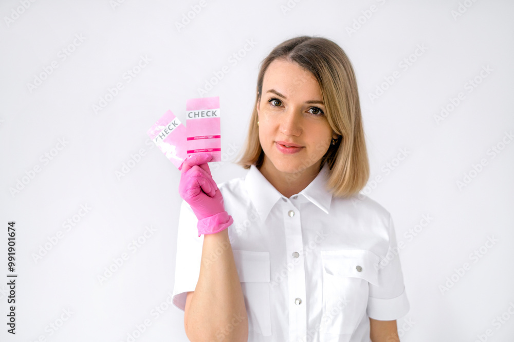 A female gynecologist in pink latex gloves holds pregnancy tests in hand