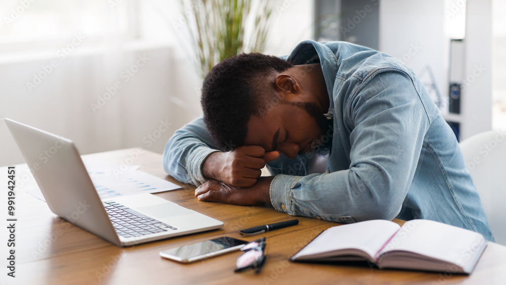 Overworking concept. Tired african american businessman sleeping at workplace in office, exhausted after hard project Overworking concept. Tired african american businessman sleeping at workplace in office, exhausted after hard project