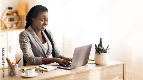 Successful businesslady working on laptop in modern office, typing on keyboard and smiling, free space photo