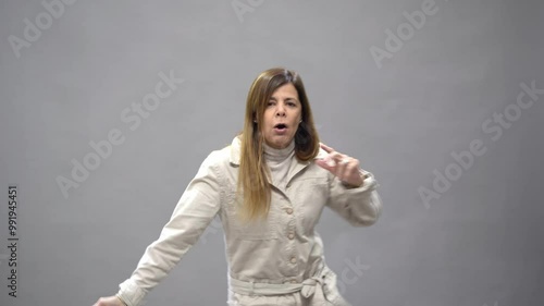 Mid-adult woman dancing gracefully in a studio against a gray background