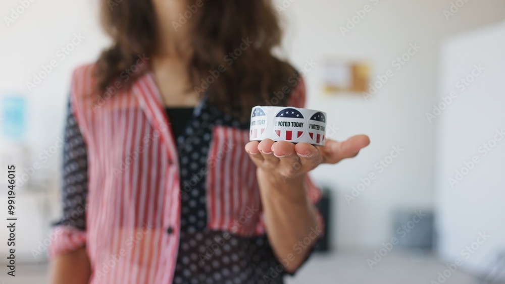 Girl in shirt with American print standing in front of camera. Woman holding roll of stickers with words Girl in shirt with American print standing in front of camera. Woman holding roll of stickers with words