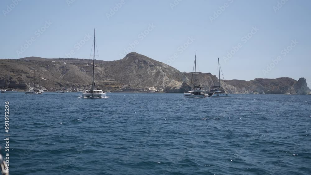 Slow motion shot of a catamaran exploring the Santorini Coastline during summer Slow motion shot of a catamaran exploring the Santorini Coastline during summer