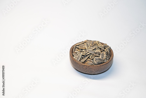 Roasted, salted sunflower seeds in a bowl on a white background.