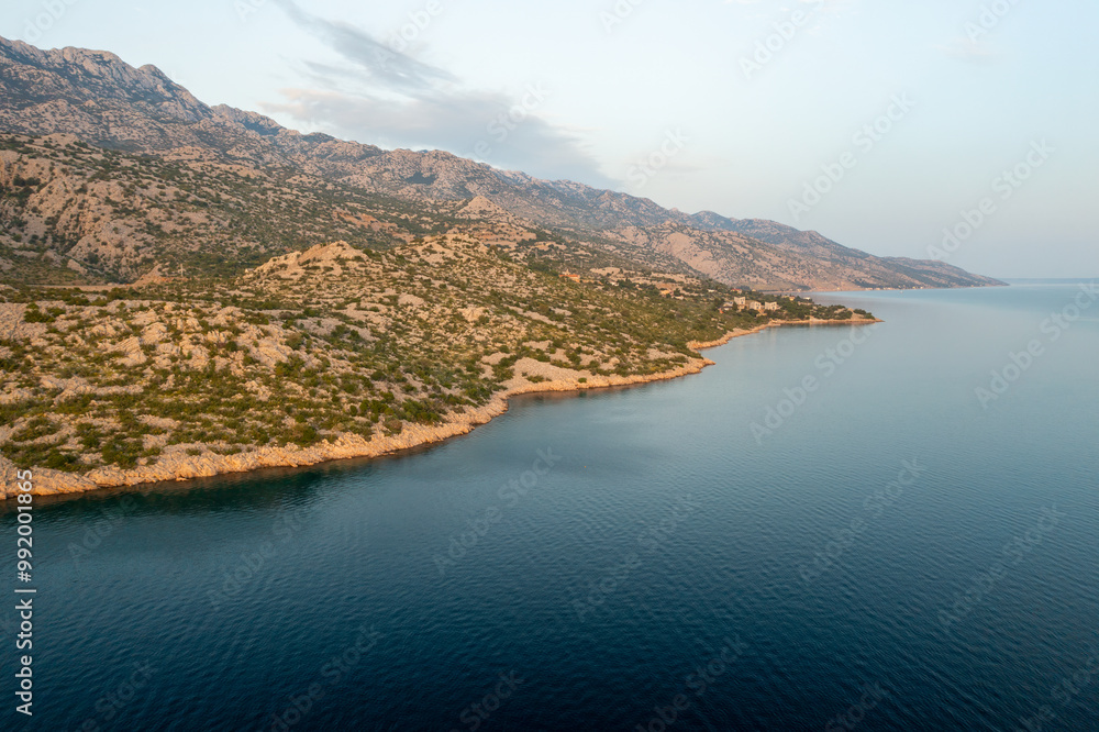 Aerial view of a serene coastline with rocky hills at sunset. Aerial view of a serene coastline with rocky hills at sunset.