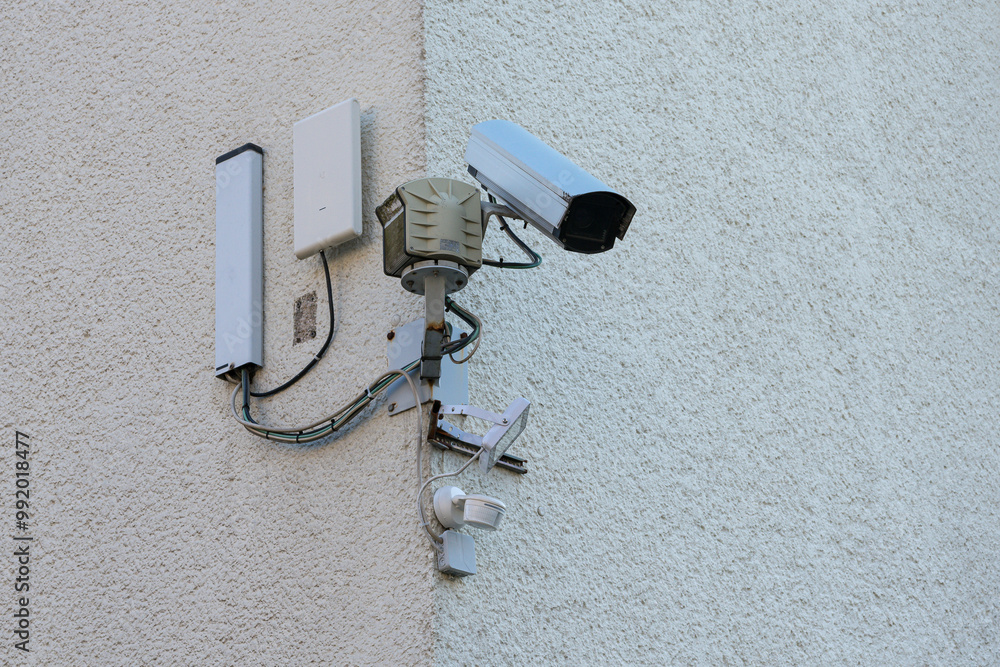 Security camera mounted on a building corner monitoring outdoor area Security camera mounted on a building corner monitoring outdoor area