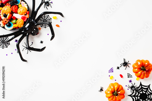 Halloween flat lay composition with spiders, sweets, pumpkins on white background. Top view with copy space.