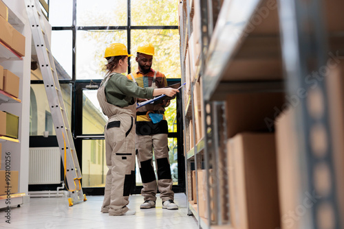 Stockroom employees working at warehouse inventory, checking logistics report before start shipping packages. African american supervisor analzing checklist, preparing customers orders with manager photo