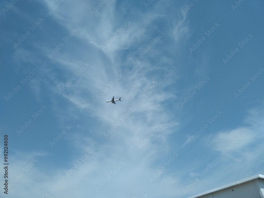 Blue sky background, with white clouds and very small plane in the distance Blue sky background, with white clouds and very small plane in the distance