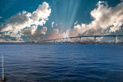 San Diego bay and the Coronado Bridge with ships sailing on blue ocean water, office buildings and skyscrapers along the coast at sunset at Coronado Tidelands Park in Coronado California photo