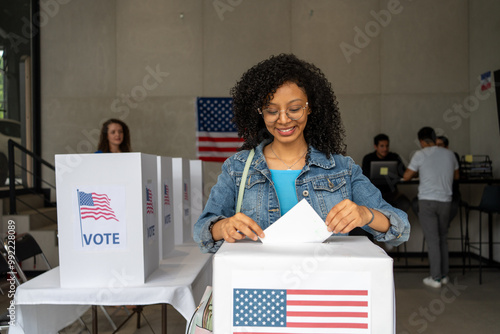 portrait of a young african american woman voting in the us election, placing vote ballot in the polling box, vote in America. Concept of usa choice, democracy and freedom