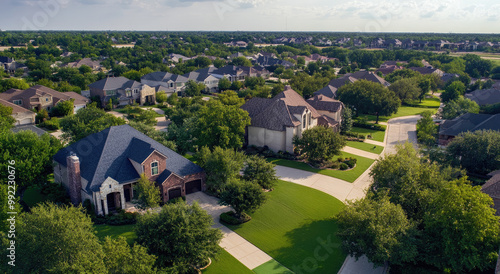 An aerial view of an upscale neighborhood in Paris, Texas, with homes and lawns, trees and street lights, captured from above by a drone